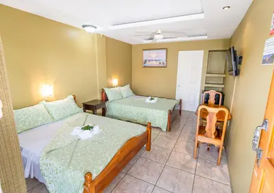 a hotel room with two beds and a chair at Hotel Le Priss in Manuel Antonio