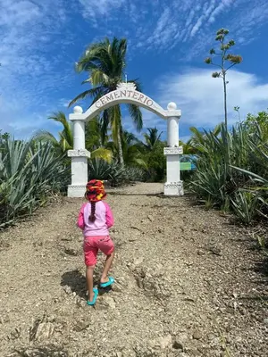 a little girl standing in front of a sign at Deer House Cabuya in Cabuya