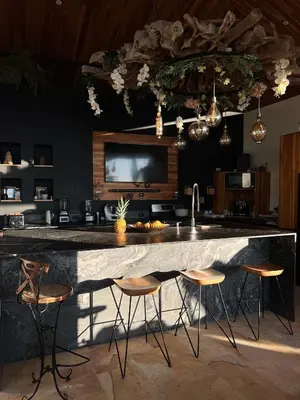 a kitchen with a large marble counter with stools at Monkey House in Dominicalito