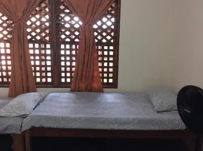 a bed in a room with two windows at Cabinas Balcon del Mar Tortuguero in Tortuguero