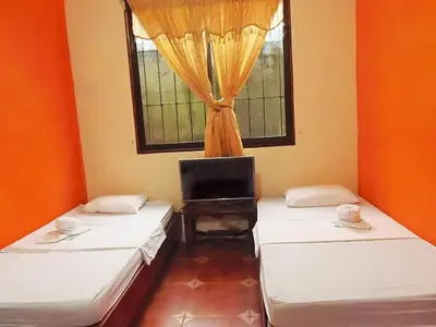 two beds in a room with a window at Cabinas El Muellecito in Tortuguero