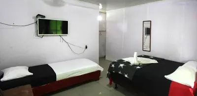 a room with two beds and a flat screen tv at Cabinas El Muellecito in Tortuguero
