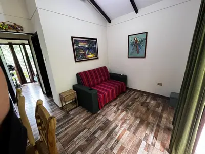 a living room with a red couch and wooden floors at Casa Colibrí in Tilarán