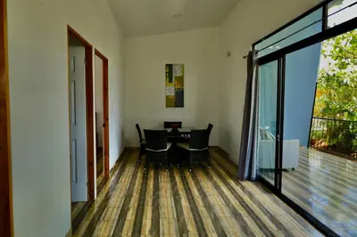 an open living room with a table and a balcony at Hills House Pinilla Guanacaste in San José Pinilla