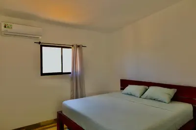 a bedroom with a bed with two pillows and a window at Hills House Pinilla Guanacaste in San José Pinilla