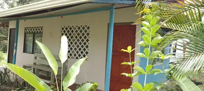 a small house with a blue and white door at Hospedaje Meryscar in Tortuguero