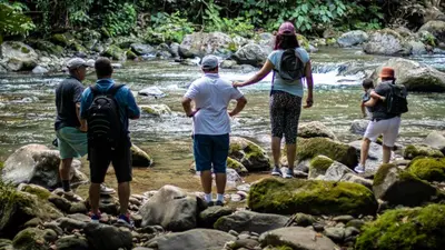 a group of people standing on rocks by a river at Hotel Rancho Cerro Azul in Fortuna