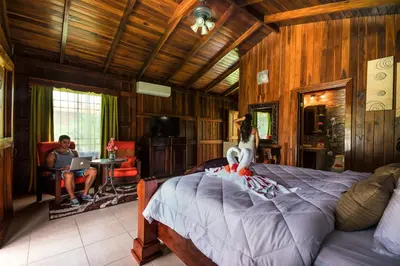 a woman sitting on a bed in a room at Hotel Rancho Cerro Azul in Fortuna