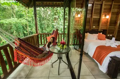 a woman sitting in a hammock on a porch at Hotel Rancho Cerro Azul in Fortuna