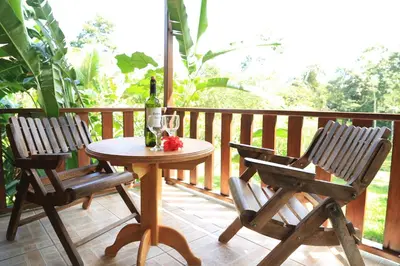 a table and chairs on a porch with a bottle of wine at Hotel Rancho Cerro Azul in Fortuna