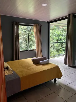 a bedroom with a bed and a large window at Cabaña Magui. in Aguas Zarcas