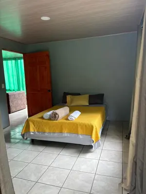 a bedroom with a bed with a yellow blanket at Cabaña Magui. in Aguas Zarcas