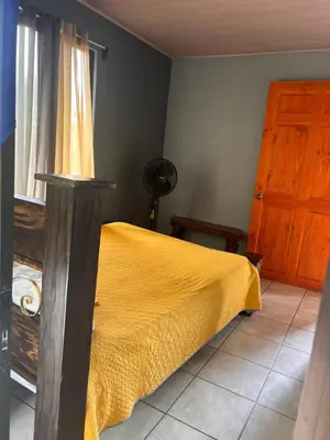 a bedroom with a bed with a yellow bedspread and a door at Cabaña Magui. in Aguas Zarcas