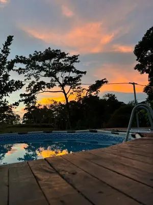 a swimming pool with a sunset in the background at Cabaña Magui. in Aguas Zarcas