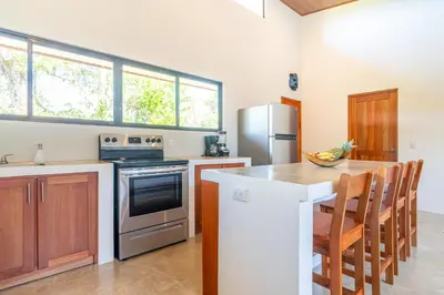 a kitchen with a table and a stove and a refrigerator at Luxury 2 bedroom, walking distance to beach in Uvita