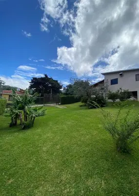 a yard with green grass and a white house at Peace Garden Apartment in Monteverde Costa Rica