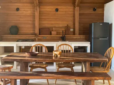 a kitchen with a wooden table with chairs and a refrigerator at Purapura Santa Teresa in Santa Teresa Beach