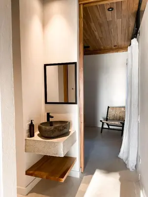 a bathroom with a stone sink and a mirror at Purapura Santa Teresa in Santa Teresa Beach