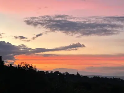 a sunset in the sky over a forest at Cabaña mirador Jacuzzi in Robles