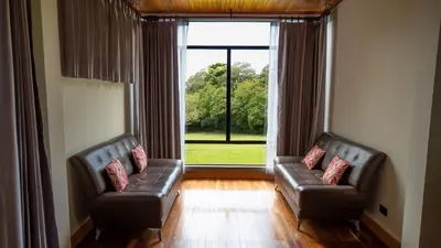 a living room with two leather couches and a large window at Fondavela Hotel in Monteverde Costa Rica