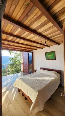 a bedroom with a large bed with a balcony at Cabaña Vista de Oro 1 in Paraíso