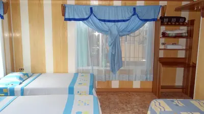 a bedroom with two beds and a window with blue curtains at Hotel Rosa De Sharon in Marsella