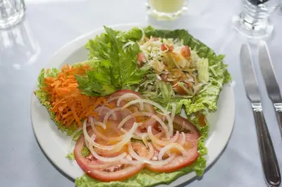 a white plate with a salad on a table at Bosque de Paz Reserva Biologica in Toro Amarillo