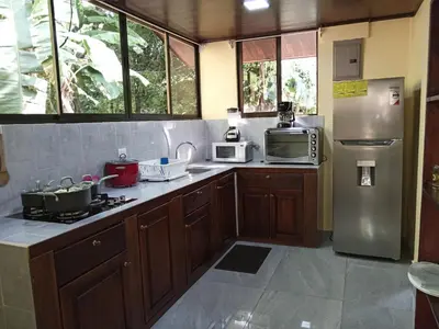 a kitchen with wooden cabinets and a stainless steel refrigerator at Casa La Montaña in Sámara