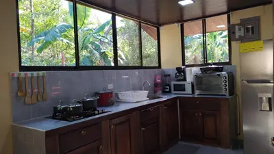 a kitchen with wooden cabinets and windows and a refrigerator at Casa La Montaña in Sámara