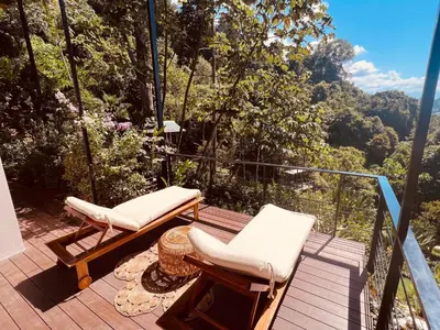 a balcony with two chairs and a view of the forest at Veranera in Uvita