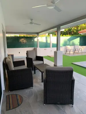 a patio with wicker chairs and tables and a yard at Casa Frangipani in Santa Rosa de Tamarindo in Santa Cruz