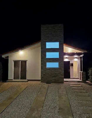 a house with a lit up window on the side of it at Casa Frangipani in Santa Rosa de Tamarindo in Santa Cruz