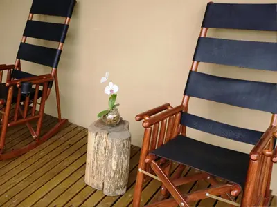 two rocking chairs and a stump with a flower in a vase at Out of Bounds Boutique Hotel in San José