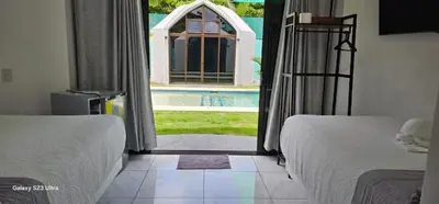 a bedroom with two beds and a view of a pool at Alborada Boutique Stay in Uvita