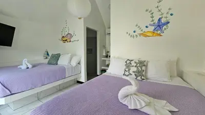 a bedroom with two beds with purple sheets and a swan at Alborada Boutique Stay in Uvita