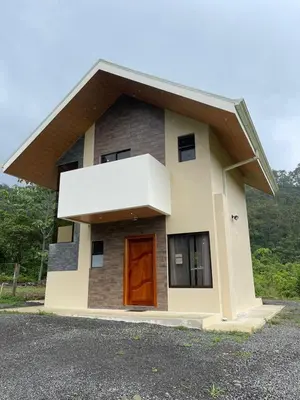 a small house with a brown door on a road at Casa Colibrí in Bijagua