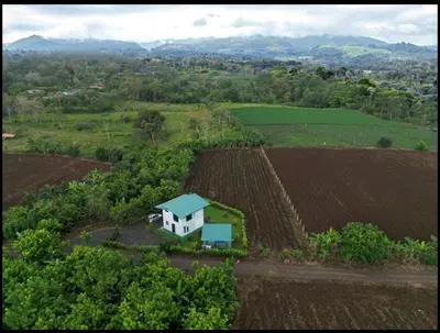 a house in the middle of a field at Arenal Nephelium Country Home, Refugio rural con piscina, jacuzzi y balcón con hermosas vistas al Volcán Arenal, en una finca privada in Fortuna