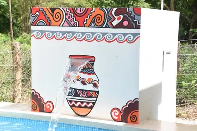 a water fountain in a pool next to a colorful vase at Guaitil Chorotega House, acogedora y tranquila in Santa Cruz