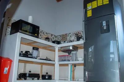 a small kitchen with a microwave and a refrigerator at Guaitil Chorotega House, acogedora y tranquila in Santa Cruz
