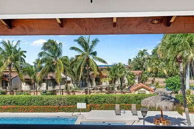 a view of a resort with a swimming pool and palm trees at Stylish 2-Bedroom Beach Condo with Ocean-View Deck, Lush Pool Area & 2-Minute Walk to Flamingo Beach in Playa Flamingo