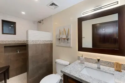 a bathroom with a toilet and a sink and a mirror at Stylish 2-Bedroom Beach Condo with Ocean-View Deck, Lush Pool Area & 2-Minute Walk to Flamingo Beach in Playa Flamingo
