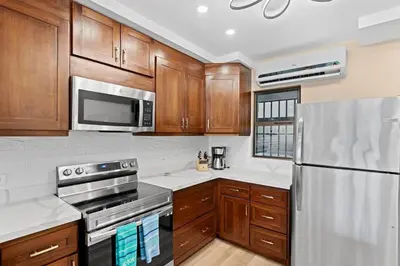 a kitchen with wooden cabinets and stainless steel appliances at Stylish 2-Bedroom Beach Condo with Ocean-View Deck, Lush Pool Area & 2-Minute Walk to Flamingo Beach in Playa Flamingo