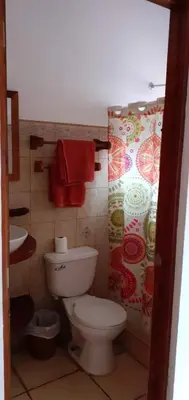 a bathroom with a toilet and a red towel at Las cabinas del sueño in Nicoya