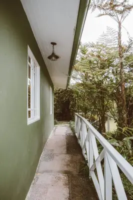 a hallway of a green building with a white fence at Cabin at Los Titos Coffee Farm in Recreo