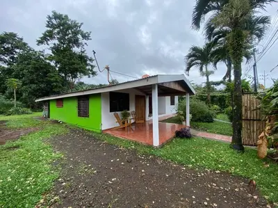 a small green and white house with a porch at Jardín Del Bosque in Bijagua