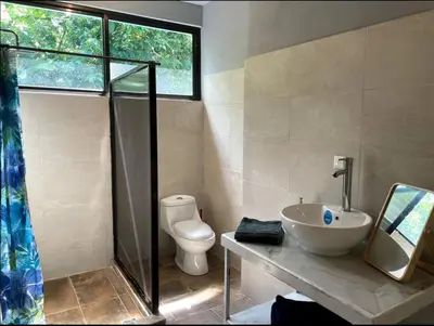 a bathroom with a sink and a toilet and a window at Casa Patricia in Uvita