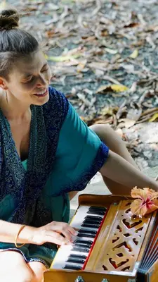 a woman is sitting next to a piano at Casa Patricia in Uvita