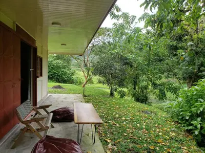 a porch of a house with a table and a bench at Studio House in Eco-Farm: nature, relaxing, hiking in Turrialba