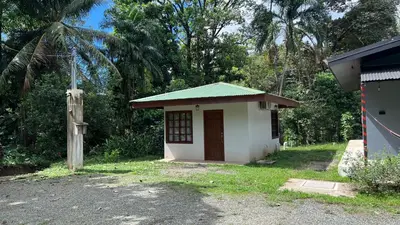 a small white building with a green roof at Cabaña junto al río in Naranjito