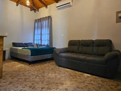 a living room with a couch and a bed at Cabaña junto al río in Naranjito